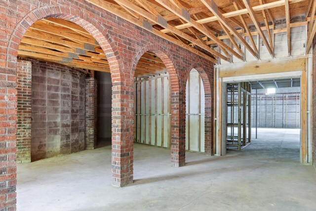 misc room with concrete flooring and brick wall