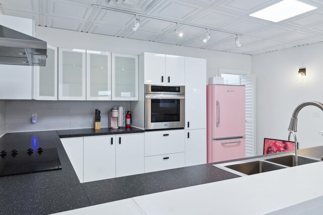 kitchen featuring white fridge, range hood, white cabinets, oven, and black electric cooktop