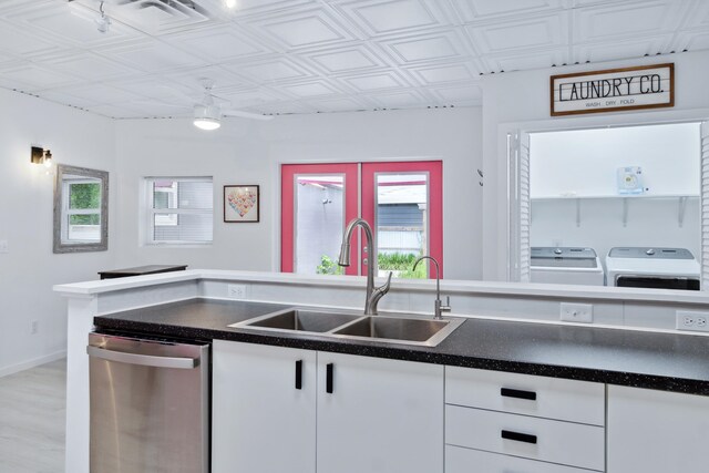 kitchen with separate washer and dryer, dishwasher, sink, white cabinetry, and light hardwood / wood-style flooring