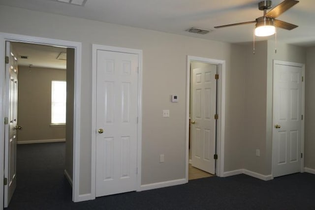 unfurnished bedroom with ceiling fan and dark carpet