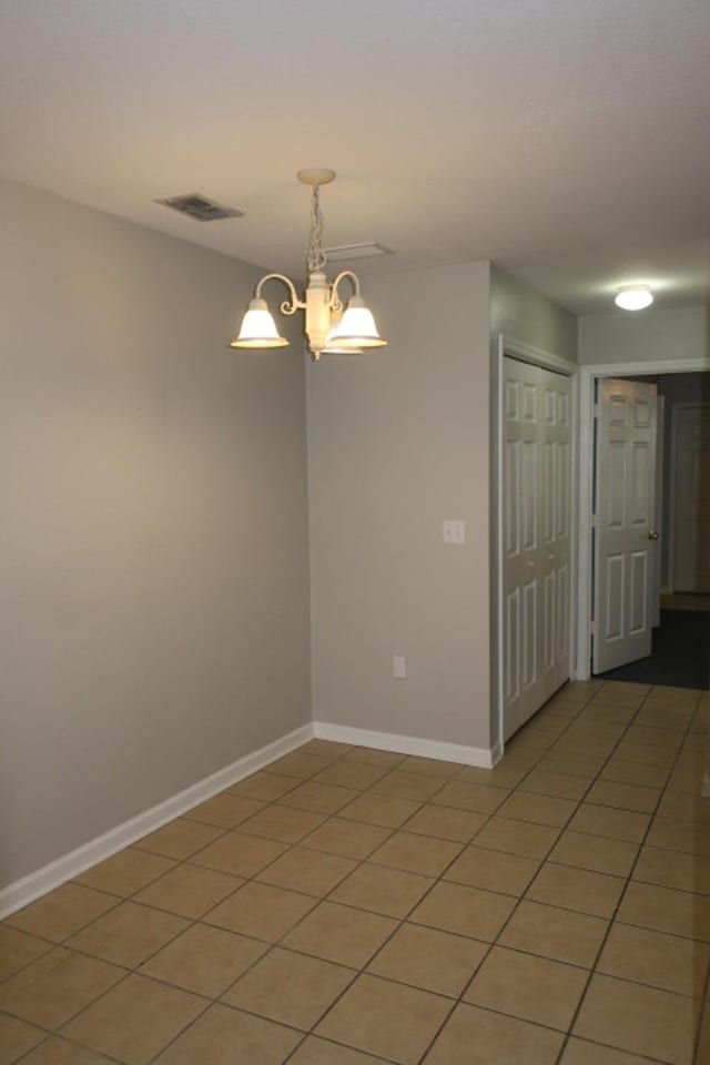 unfurnished room featuring tile patterned floors and a chandelier