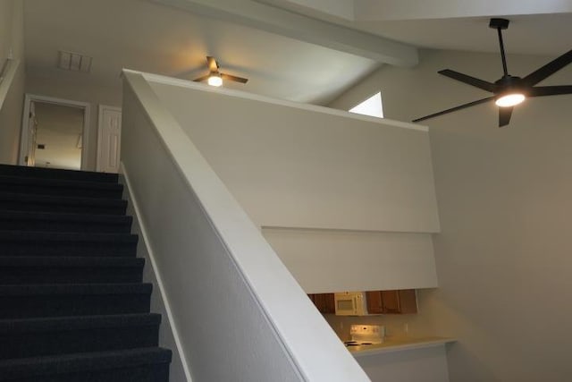 staircase with ceiling fan and vaulted ceiling with beams