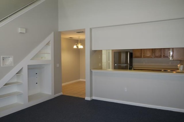 kitchen with built in shelves, carpet flooring, stainless steel fridge, and an inviting chandelier