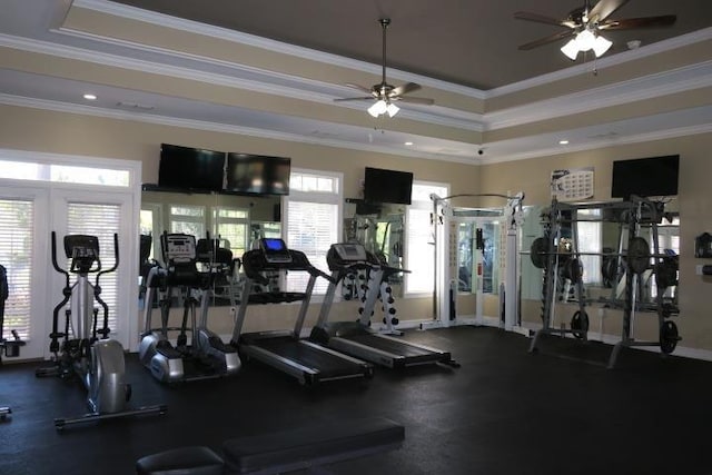 workout area featuring a tray ceiling, ornamental molding, and ceiling fan