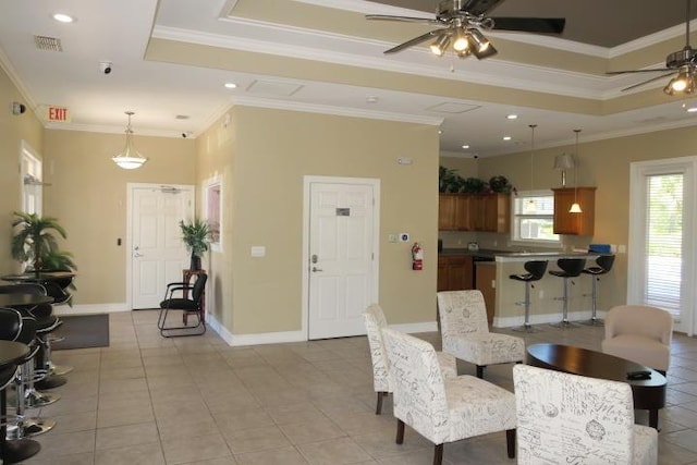 interior space with crown molding, ceiling fan, a tray ceiling, and light tile patterned flooring