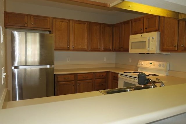 kitchen featuring white appliances, kitchen peninsula, and sink