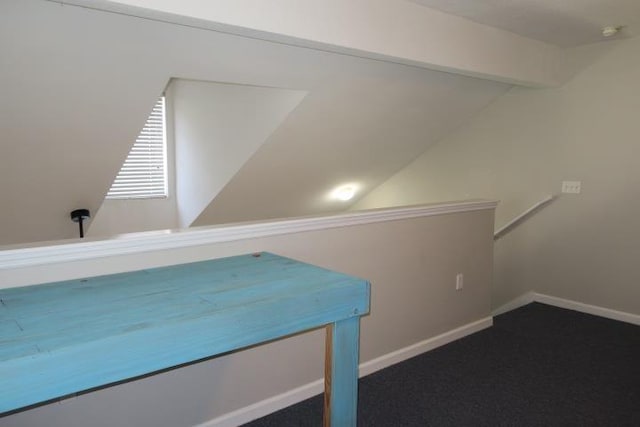 interior space featuring dark colored carpet and vaulted ceiling with beams