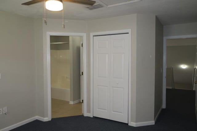 unfurnished bedroom featuring ceiling fan, a closet, and dark colored carpet