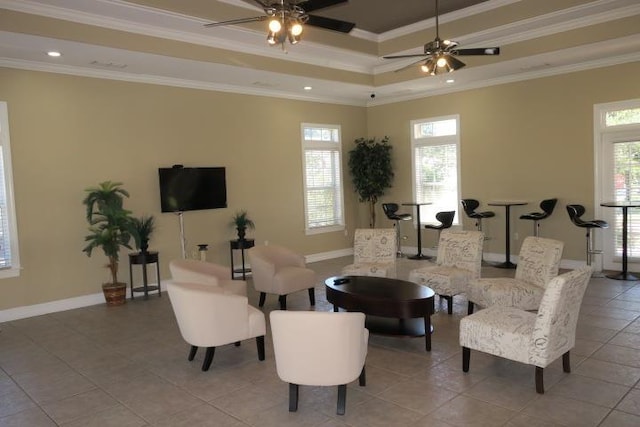 living room with crown molding, ceiling fan, a tray ceiling, and light tile patterned flooring