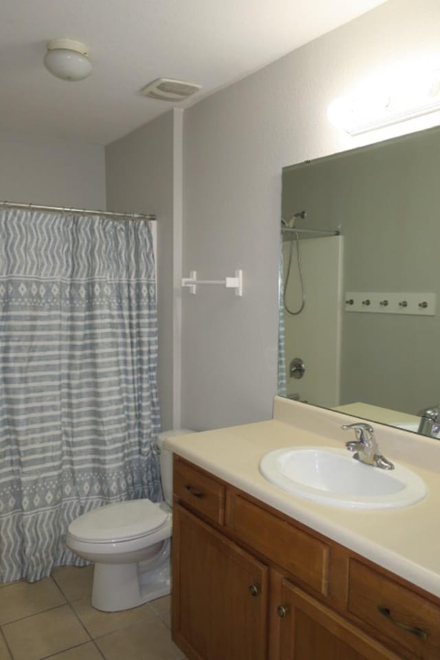 bathroom featuring tile patterned flooring, vanity, toilet, and walk in shower