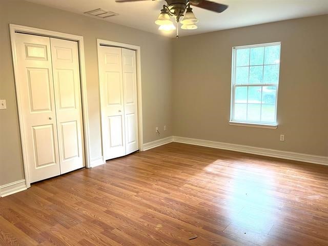 29 Chippewa Rd, Crawfordville, FL 32327 - unfurnished bedroom featuring two closets, wood finished floors, and ceiling fan