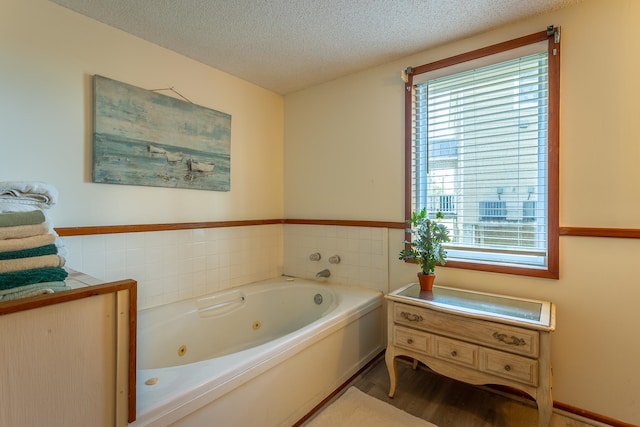 bathroom with a tub to relax in, a textured ceiling, and wood-type flooring