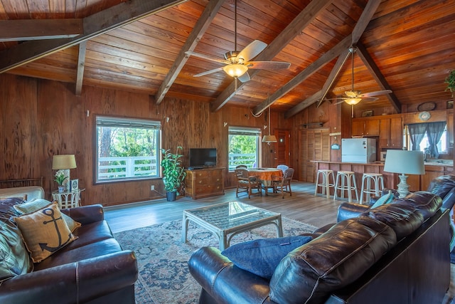 living room with light wood-type flooring, wooden walls, vaulted ceiling with beams, and wood ceiling