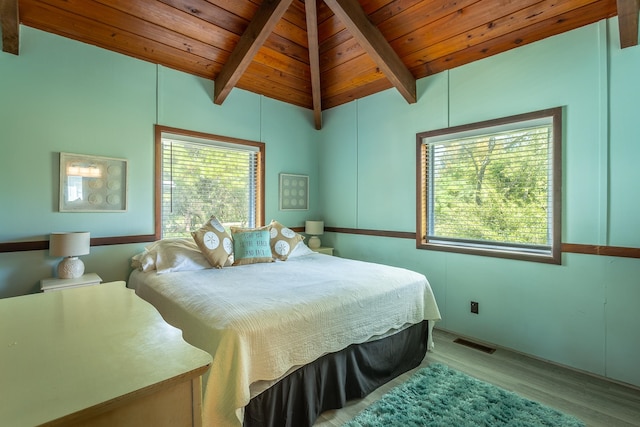 bedroom with light hardwood / wood-style floors, vaulted ceiling with beams, and wooden ceiling