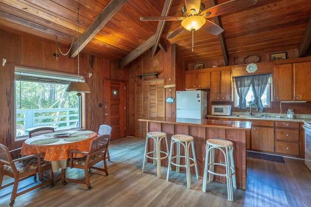 kitchen featuring lofted ceiling with beams, dark hardwood / wood-style flooring, white appliances, and wooden walls