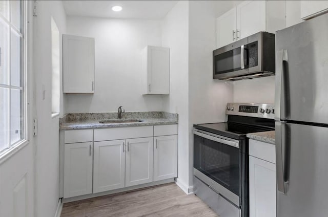 kitchen featuring sink, white cabinetry, stainless steel appliances, and light wood-type flooring