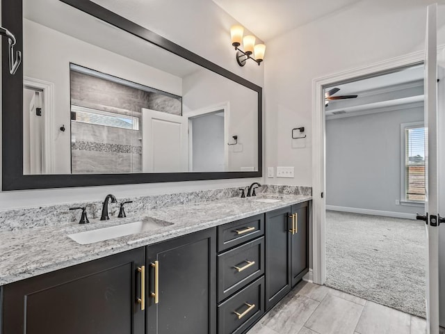 full bath with double vanity, a sink, and baseboards