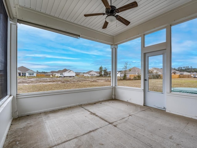 unfurnished sunroom featuring ceiling fan and a residential view