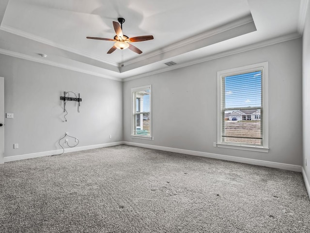 carpeted empty room featuring a tray ceiling and baseboards