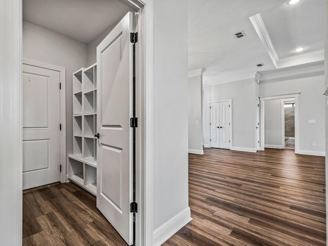 hallway with baseboards, visible vents, dark wood-type flooring, and crown molding