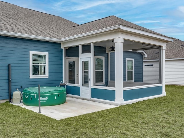 back of house with a shingled roof, a sunroom, and a lawn