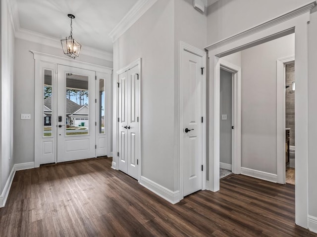 foyer with dark wood-type flooring, a chandelier, crown molding, and baseboards