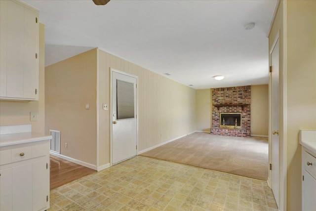 unfurnished living room featuring light carpet, baseboards, a fireplace, and visible vents