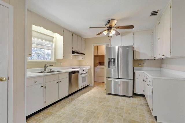 kitchen featuring stainless steel appliances, light countertops, under cabinet range hood, washing machine and dryer, and a sink