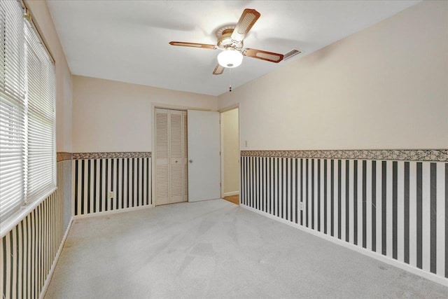 empty room featuring carpet, visible vents, ceiling fan, and wallpapered walls