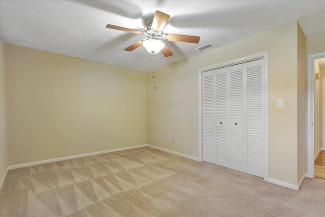 unfurnished bedroom with visible vents, baseboards, a ceiling fan, light colored carpet, and a closet