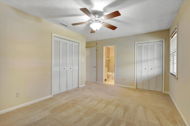 unfurnished bedroom featuring carpet floors, visible vents, baseboards, and two closets