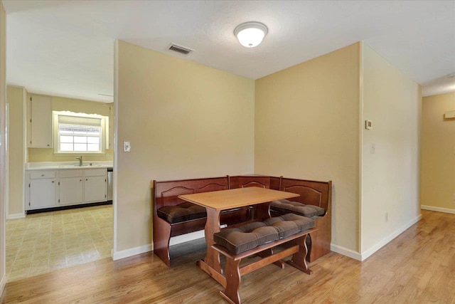 dining area featuring light wood finished floors, visible vents, and baseboards