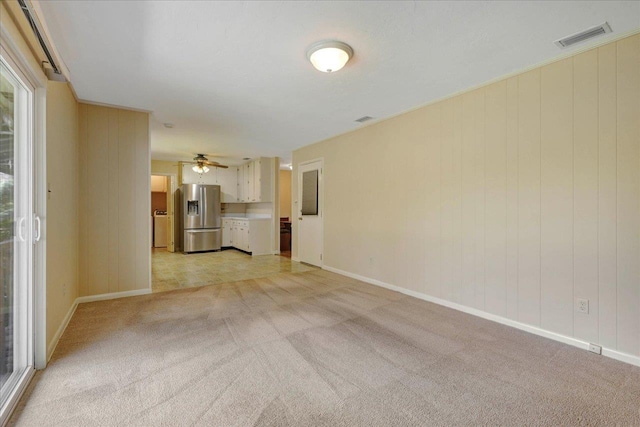 unfurnished living room featuring baseboards, visible vents, and light colored carpet