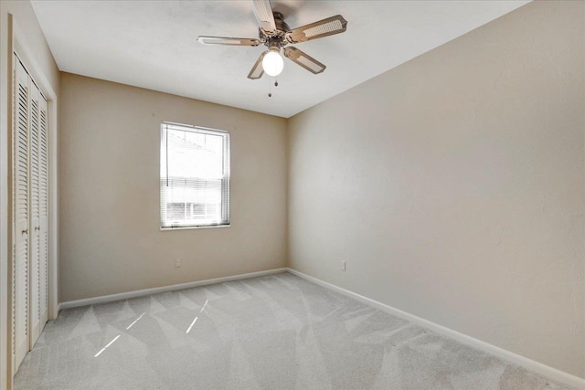 unfurnished bedroom featuring a ceiling fan, baseboards, a closet, and light colored carpet