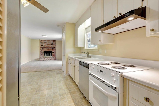 kitchen featuring white electric stove, stainless steel dishwasher, a brick fireplace, a sink, and under cabinet range hood