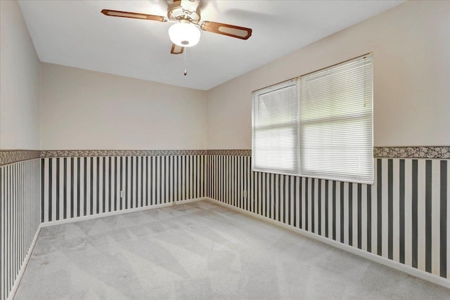 empty room featuring carpet floors, wainscoting, and wallpapered walls