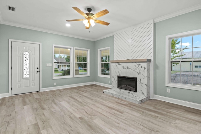 unfurnished living room featuring visible vents, ornamental molding, wood finished floors, ceiling fan, and a premium fireplace