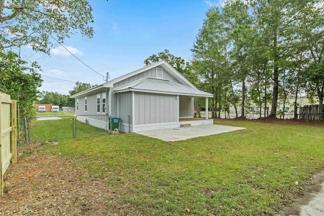 rear view of house featuring a patio, a fenced backyard, board and batten siding, and a yard