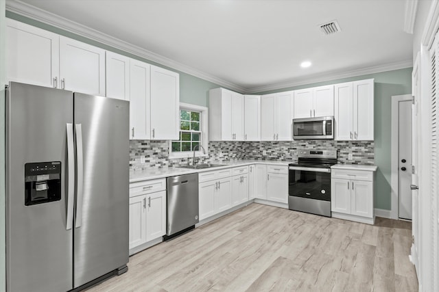 kitchen with white cabinets, appliances with stainless steel finishes, a sink, light countertops, and visible vents