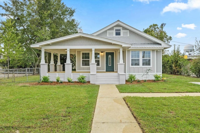 bungalow featuring board and batten siding, fence, covered porch, and a front lawn