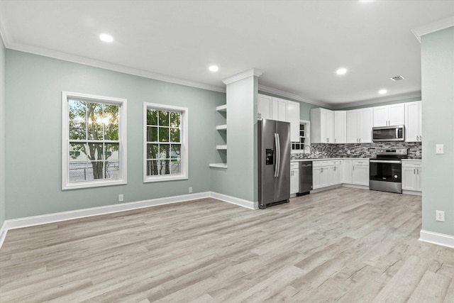 kitchen with appliances with stainless steel finishes, tasteful backsplash, white cabinets, light wood finished floors, and ornamental molding