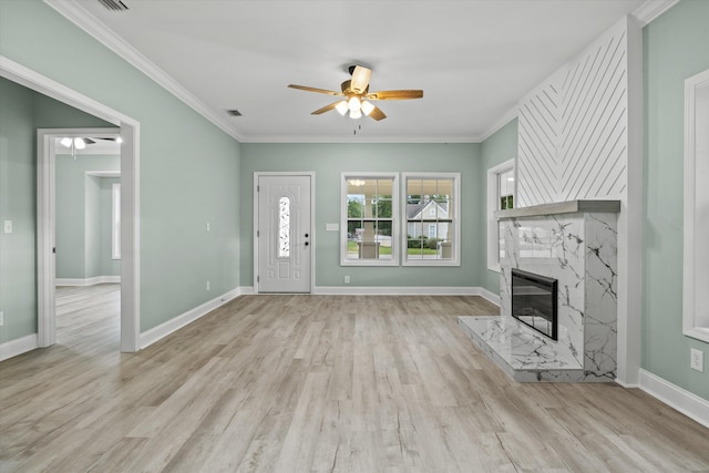unfurnished living room featuring crown molding, a fireplace, baseboards, ceiling fan, and light wood-style flooring