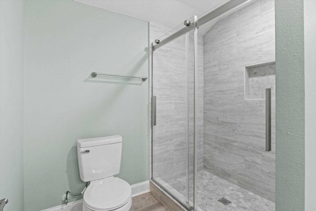bathroom with baseboards, a stall shower, and toilet