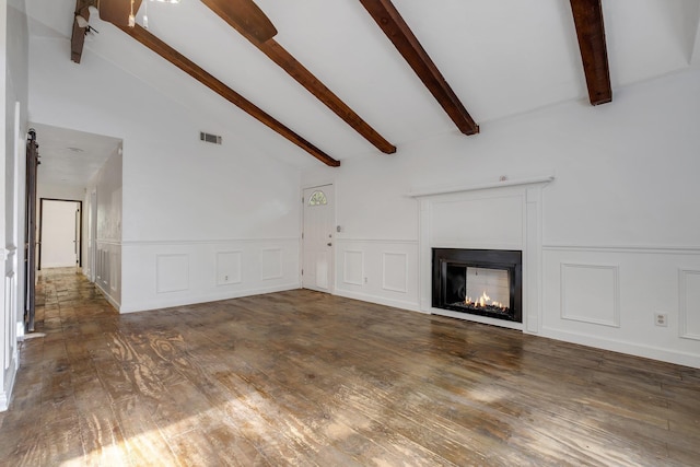3200 Tallavana Trl, Havana, FL 32333 - unfurnished living room featuring beamed ceiling, a decorative wall, hardwood / wood-style floors, wainscoting, and a warm lit fireplace