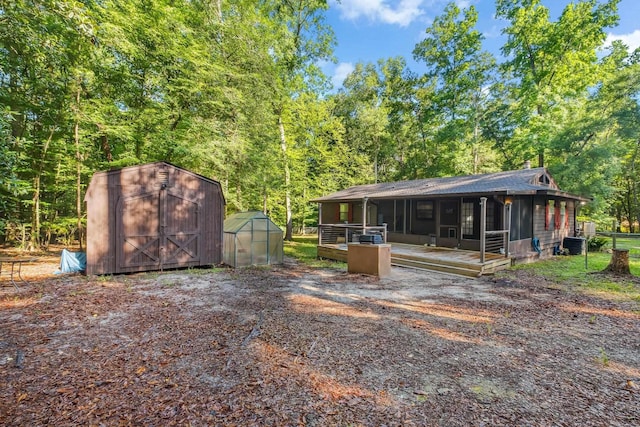 3200 Tallavana Trl, Havana, FL 32333 - back of property with an outdoor structure, a greenhouse, a deck, roof with shingles, and a view of trees