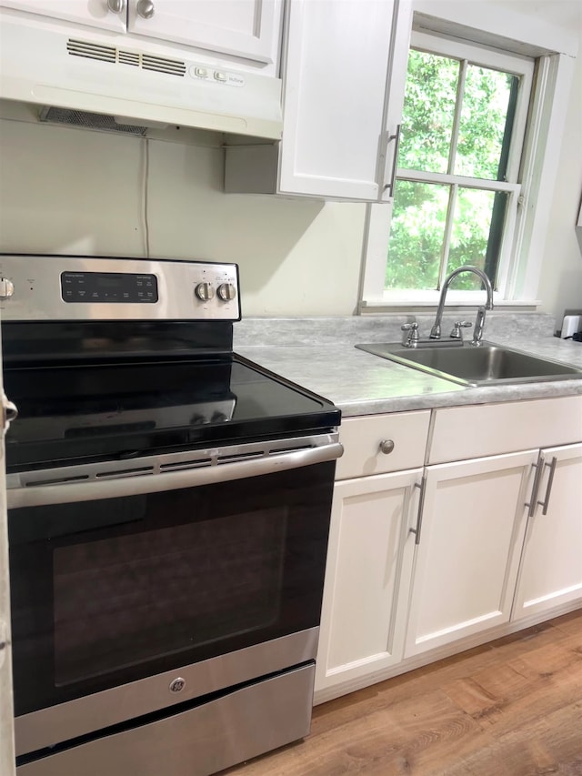 kitchen with white cabinets, sink, light hardwood / wood-style flooring, and electric stove