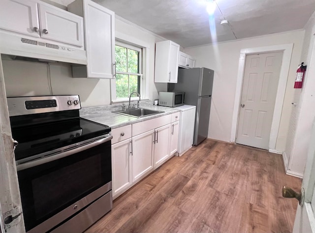 kitchen with white cabinets, hardwood / wood-style floors, stainless steel appliances, and sink