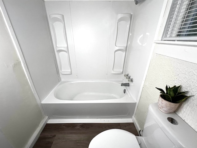 bathroom featuring  shower combination, hardwood / wood-style flooring, and toilet