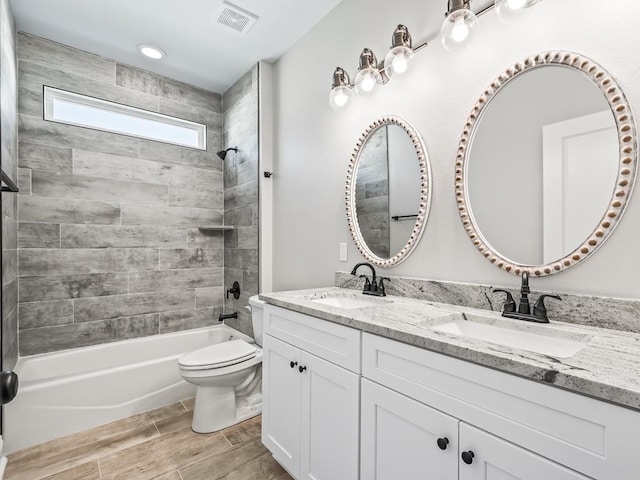 full bathroom with hardwood / wood-style floors, tiled shower / bath, toilet, and vanity