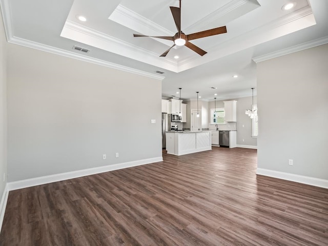 unfurnished living room featuring dark wood-type flooring, a tray ceiling, and ornamental molding